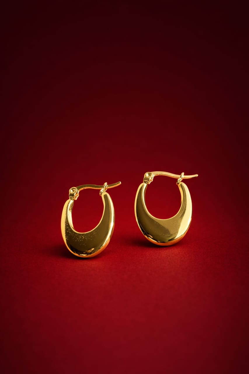 Gold-tone crescent hoop earrings displayed on red background