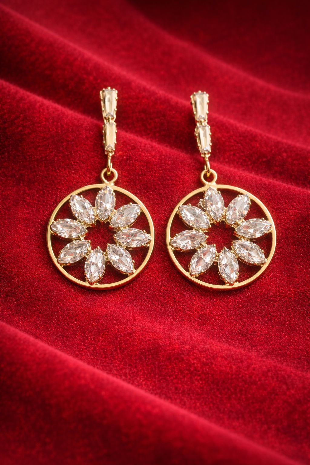 Gold-tone floral circle drop earrings with clear crystal stones on red velvet background
