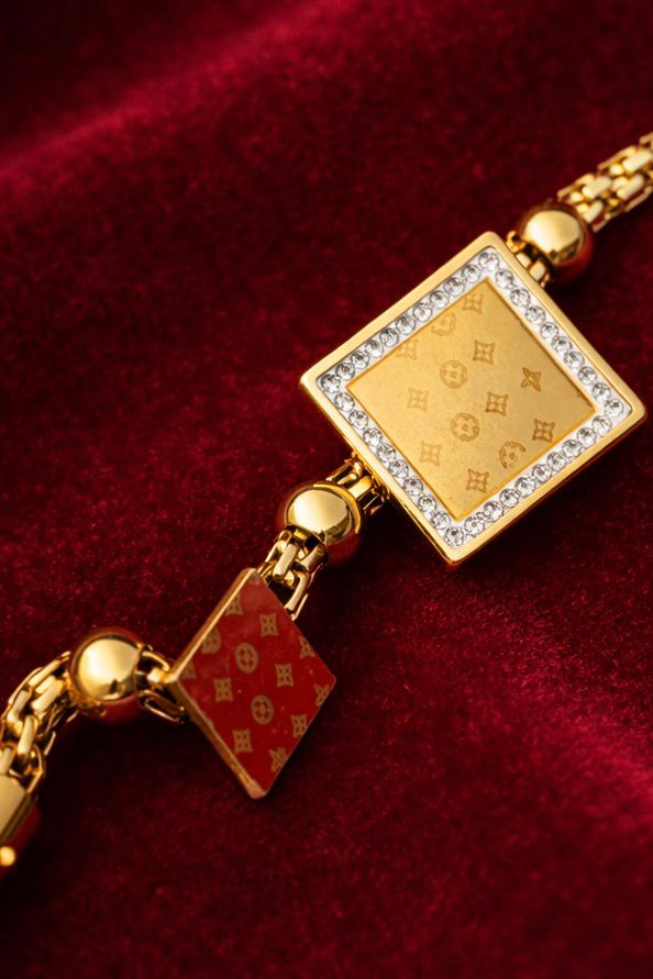 Gold bracelet with square decorative tiles and crystal-framed center piece