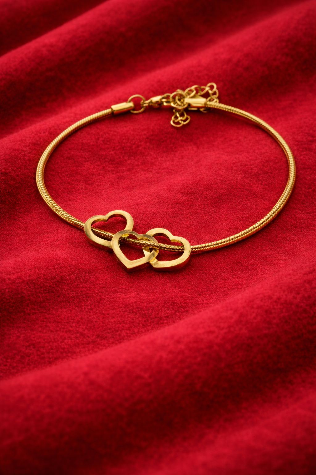 Gold plated linked hearts snake chain bracelet for women on red velvet background