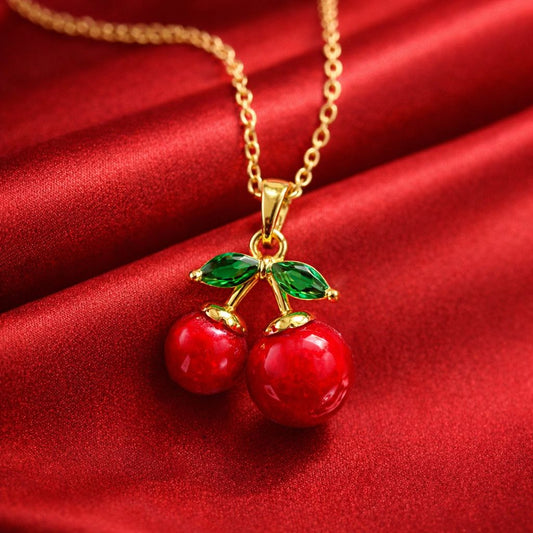 Gold necklace with cherry pendant on a red fabric background
