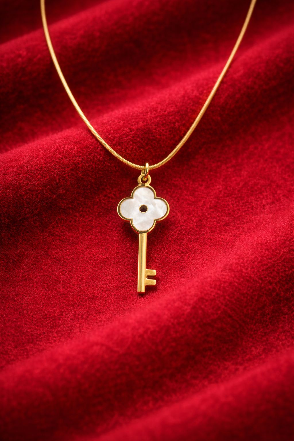Gold necklace with a key-shaped pendant on a red fabric background