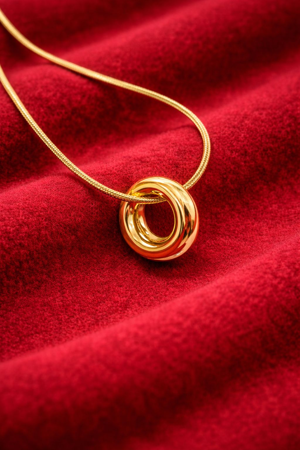 Gold plated Korean double interlocking ring pendant necklace on red velvet background