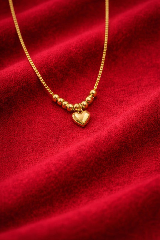 Gold necklace with a heart pendant on a red fabric background