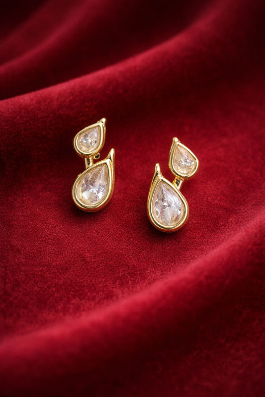 Gold teardrop earrings with clear stones on a red fabric background